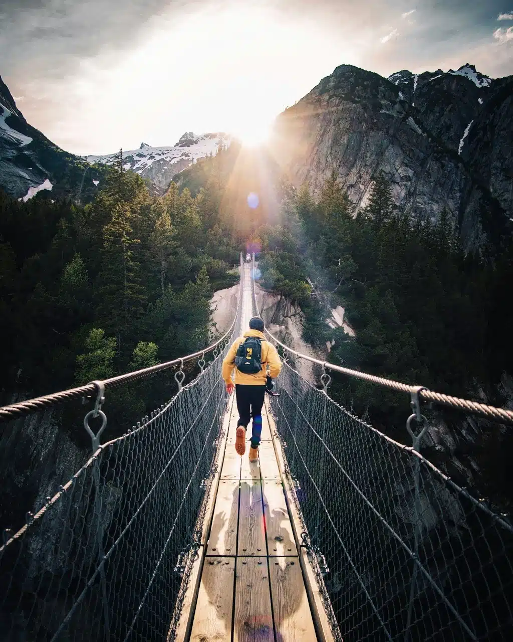 Person crossing a bridge in the mountains.